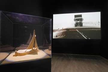 Zineb Sedira  b. 1963, France Guiding Light 2013 Single-screen projection HD video with sound (6 min. 15 sec.), model boat, sand  Installation: dimensions variable  Collection of the artist, courtesy Galerie Kamel Mennour, Paris   